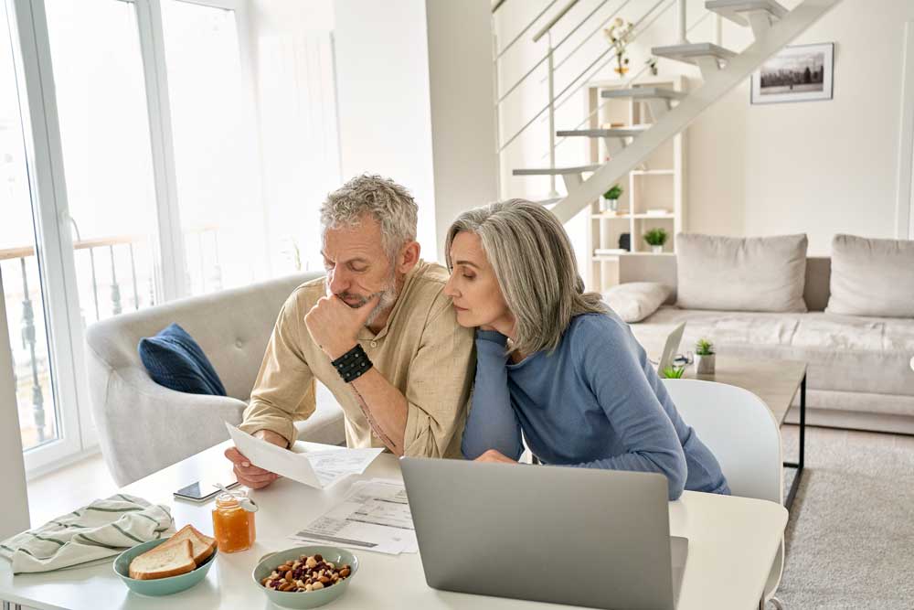 older couple looking at financial documents on a computer