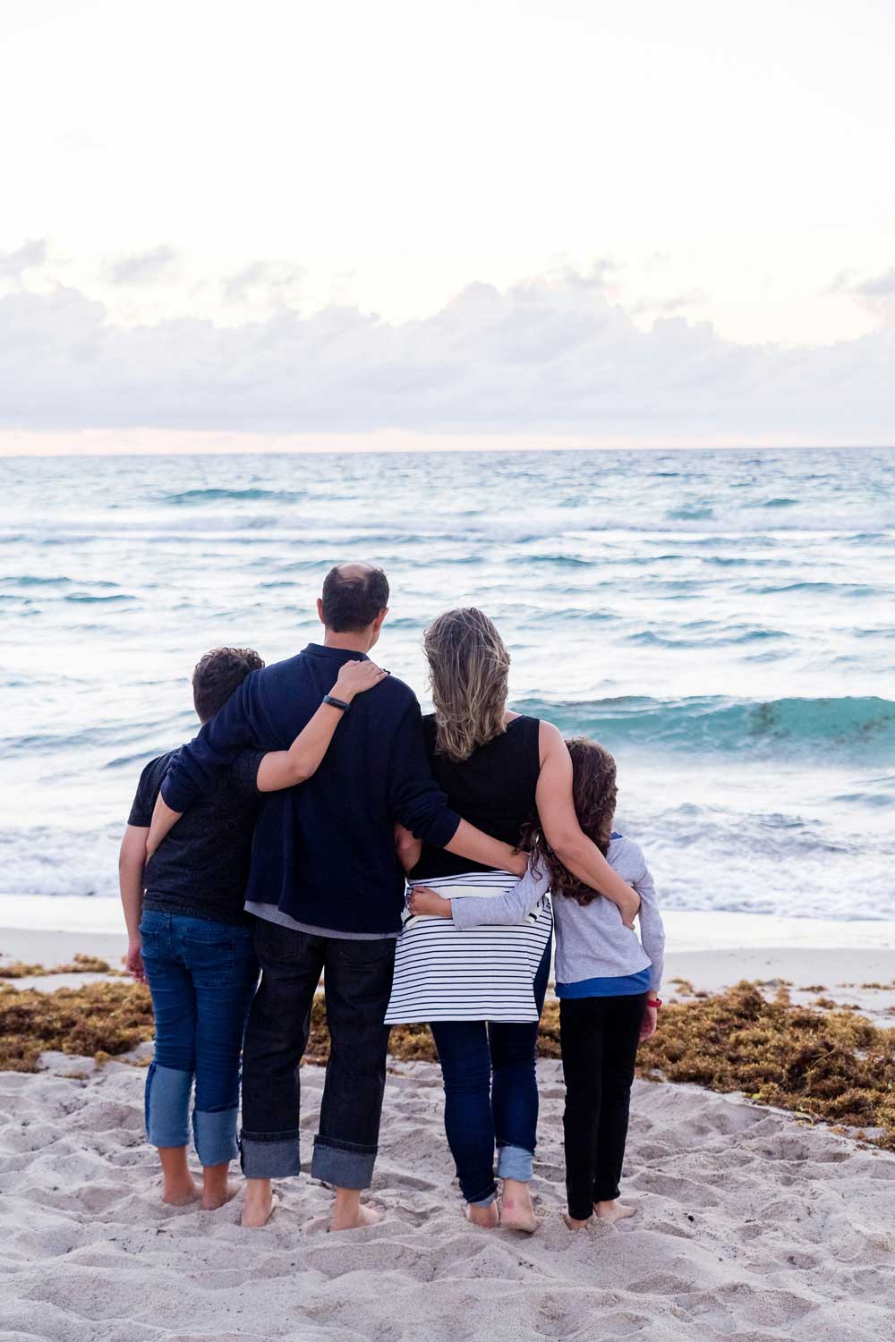 family of 4 facing the ocean on soft sand